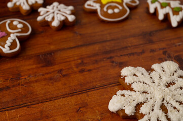 Close-up of a star-shaped gingerbread with coconut shards frosting on a brown wooden table background, various shapes of gingerbread can be seen in the background.
