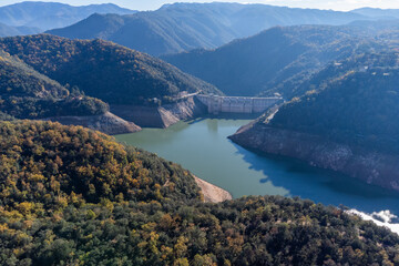 Fototapeta na wymiar Sau reservoir dam with water levels much lower than usual due to Drought impact, water crisis, water consumption, water shortage concept. Pantà de Sau, Catalonia.