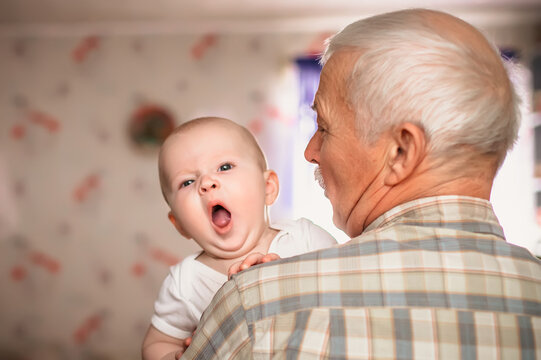 Toddler yawns. Over shoulder close up of grandfather holding his baby grandson,