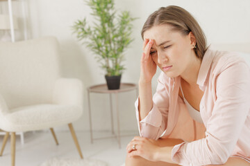 Fototapeta premium a girl in light clothes suffers from a headache holding on to her temples, migraine,