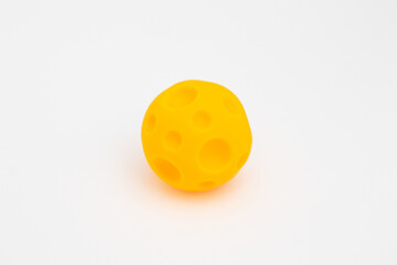 Rubber tactile ball, educational toy for babies. Yellow ball with indentations on a white background