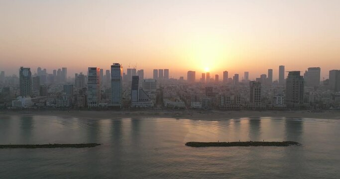 Aerial view of Tel Aviv coastline at sunrise with beautiful calm waters of The Mediterranean Sea, Waterfront hotels and light sun flare