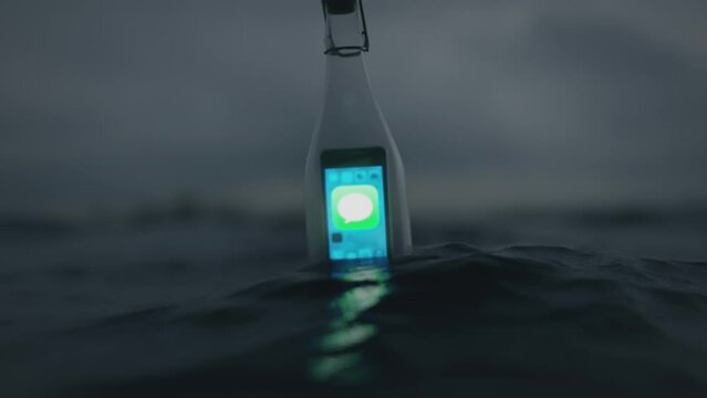 Message in a bottle. A bottle floating in the sea with a smartphone inside displaying an incoming messaege.