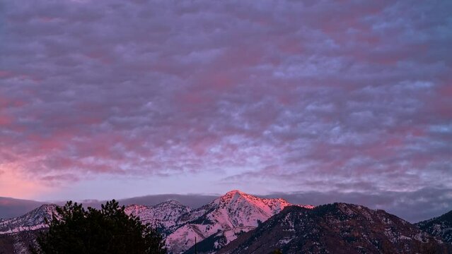 Sunset timelapse of the Wasatch Mountains in Utah with snow capped peaks.
