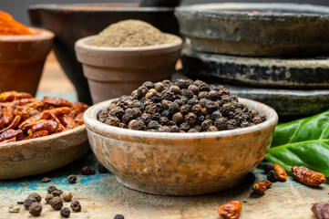 Indian spices collection, dried black peppercorns and another spices in clay bowls