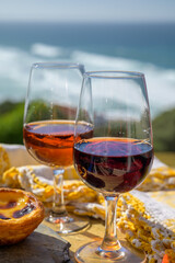 Tasting of sweet moscatel de setubal and tawny porto portuguese wine and view on blue Atlantic ocean near Sintra in Lisbon area, Portugal