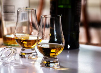 Tasting of whiskey, tulip-shaped tasting glasses with dram of Scotch single malt or blended whisky on white table
