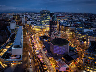 Elevated, panoramic view of the illuminated Breitscheidplatz in Berlin, Germany, with the Kaiser Wilhelm Memorial church and a Christmas Market during winter dusk time