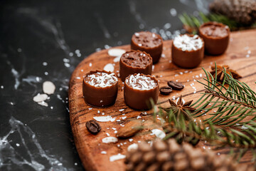 Chocolate pralines on wooden tray with christmas decorations