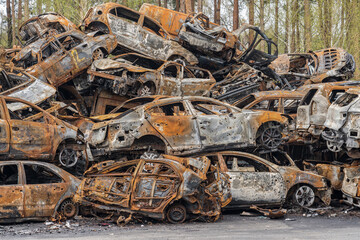 Fototapeta premium A hill of burned cars in a junkyard. Civilian cars were destroyed as a result of hostilities
