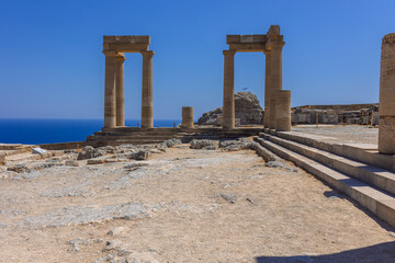 Fototapeta premium Panoramic view of ruins of ancient city of Lindos on colorful island of Rhodes, Greece. Famous tourist attraction. Ancient temple Greek architecture. High quality photo