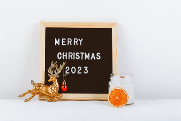 Merry Christmas lettering on letter board. Eco tree and golden deer. minimalistic new year background 2023