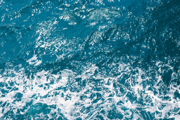 Seething sea water with waves and foam, top view. Water surface, textured background