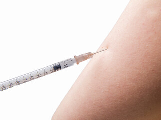 close up of vaccination with syringe in upper arm . High quality photo . focus on the needle white background 