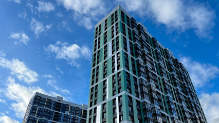Fototapeta premium Facade of the building in green and lettuce colors, geometric patterns from windows and balconies, colored wall of a modern multistory apartment building, abstract texture of the house facade