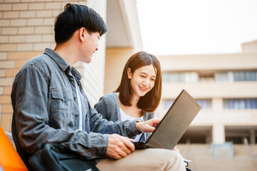 Two students are sitting at the stairs reading books to education and using laptop. Study for test preparation in University.Education, Learning, Student, Campus, University, Lifestyle concept.