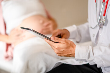 Close up of Male doctor hold patient have consultation with pregnant woman in hospital. Female gynecologist talk consult female check pregnancy before giving birth. Maternity concept.
