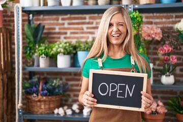 Young woman working at florist holding open sign winking looking at the camera with sexy...