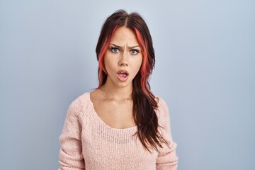 Obraz premium Young caucasian woman wearing pink sweater over isolated background in shock face, looking skeptical and sarcastic, surprised with open mouth