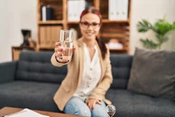 Young caucasian woman offering a glass of water looking positive and happy standing and smiling with a confident smile showing teeth