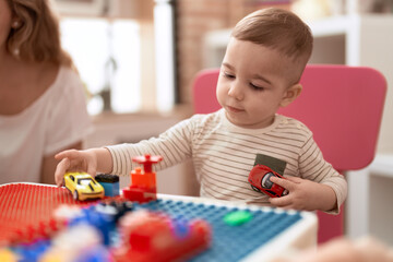 Adorable toddler playing with car toy sitting on table at kindergarten