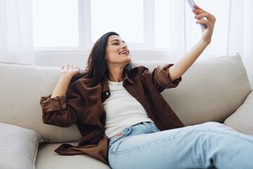 Woman blogger with phone lies at home on the couch and works freelancer online, selfie