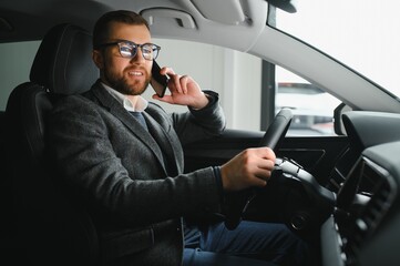 Handsome businessman driving car to airport, going on business side view, copy space. Happy man in stylish suit going to business meeting in the morning, driving his luxury car, shot from cabin.