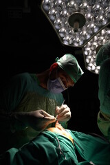 Doctor performing nose surgery in the operating room.  green dresses and black room in the operating room
