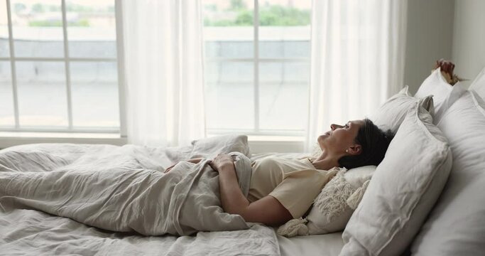 Senior single woman sleeps alone in bed, wake up, do stretching exercises, welcoming new day, enjoying good morning at home, feels refreshed. Comfortable mattress for healthy enough night sleep, rest