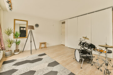 a living room with a drum on the floor in front of a white wall and wooden floor next to a large...