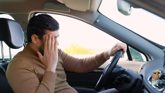 Emotions of pity and grief on the face of a young man sitting in a car. The bearded driver sits in the car and is sad. People and emotions.