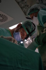 Doctor performing nose surgery in the operating room.  green dresses and black room in the operating room
