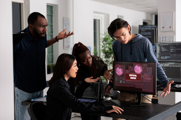 Team of it programmers having web server hacked, looking at critical error on computer monitor in...