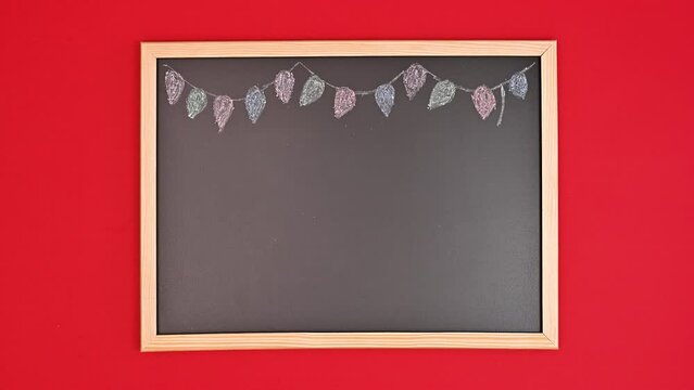 Drawing Christmas decorations on black board with colorful chalks. Stop motion. Flat lay