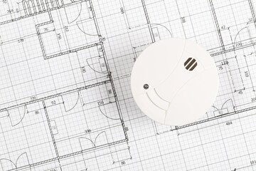 Smoke detector or fire alarm sensor on white architectural plans background, house safety or...