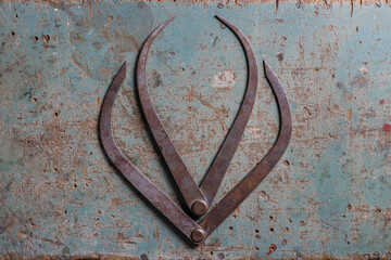 Metal woodworking compasses flat lay on a rustic suface shaped like a tulip