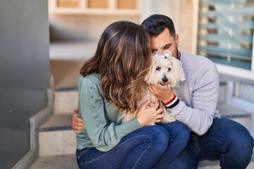 Man and woman holding dog hugging each other at street