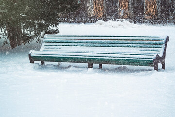 A park bench covered with snow in winter. Winter weather and snowfall