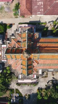 Vertical video of Drone footage of the northern part of Battambang, Cambodia. The camera is facing down at a birdeye angle over the beautiful pagoda and is ascending straight showing the Wat Keo compo