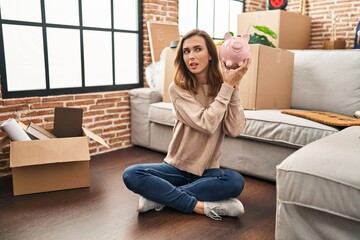 Fototapeta premium Young woman holding piggy bank at new home