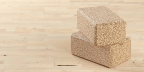 Two stacked yoga or pilates blocks made from natural cork on wooden floor background in yoga, pilates or fitness studio with copy space