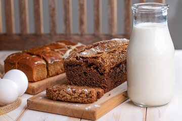 bottle of milk, eggs and a chocolate cupcake on a wooden board. Close-up.
