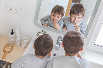 Brother morning fun male kids cleaning teeth toothbrush in front of mirror sink at bathroom
