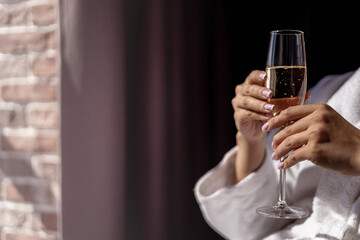 Closeup unrecognizable beautiful manicure female hands holding fizzy champagne glass relaxing