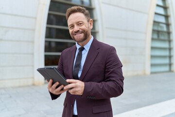 Fototapeta premium Middle age man business worker smiling confident using touchpad at street