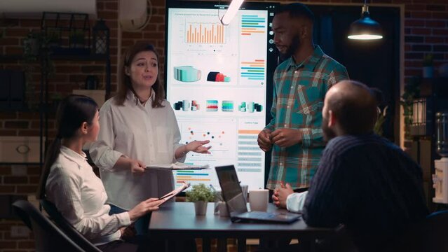 Colleagues team presenting company research statistics report, data visualization presentation. Office workers speaking in business meeting, coworkers discussion, medium shot