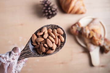 Closeup of almonds in wooden spoon with bread on wooden background, vintage tones, breadbread
