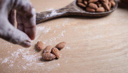Closeup of almonds in wooden spoon with bread on wooden background, vintage tones, breadbread
