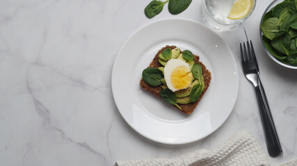 Tasty sandwich with boiled egg, avocado and spinach served on white marble table, flat lay. Space for text