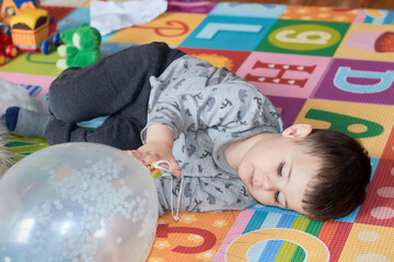 young boy playing with a balloon in his room